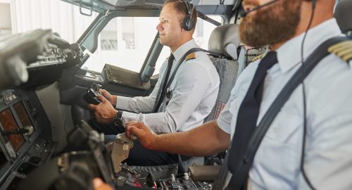 Two experienced airman in a cockpit controlling the speed with throttle lever and looking confident